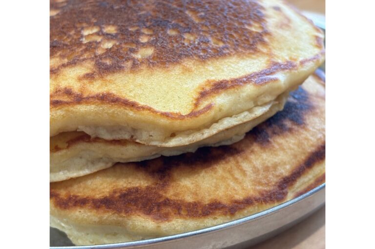 3 sourdough buttermilk pancakes staked on a stainless steel plate