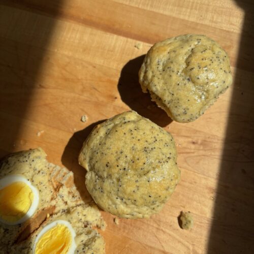 2 Sourdough Discard Lemon Poppyseed Muffins, one cut in the middle with a hardboiled egg inside.