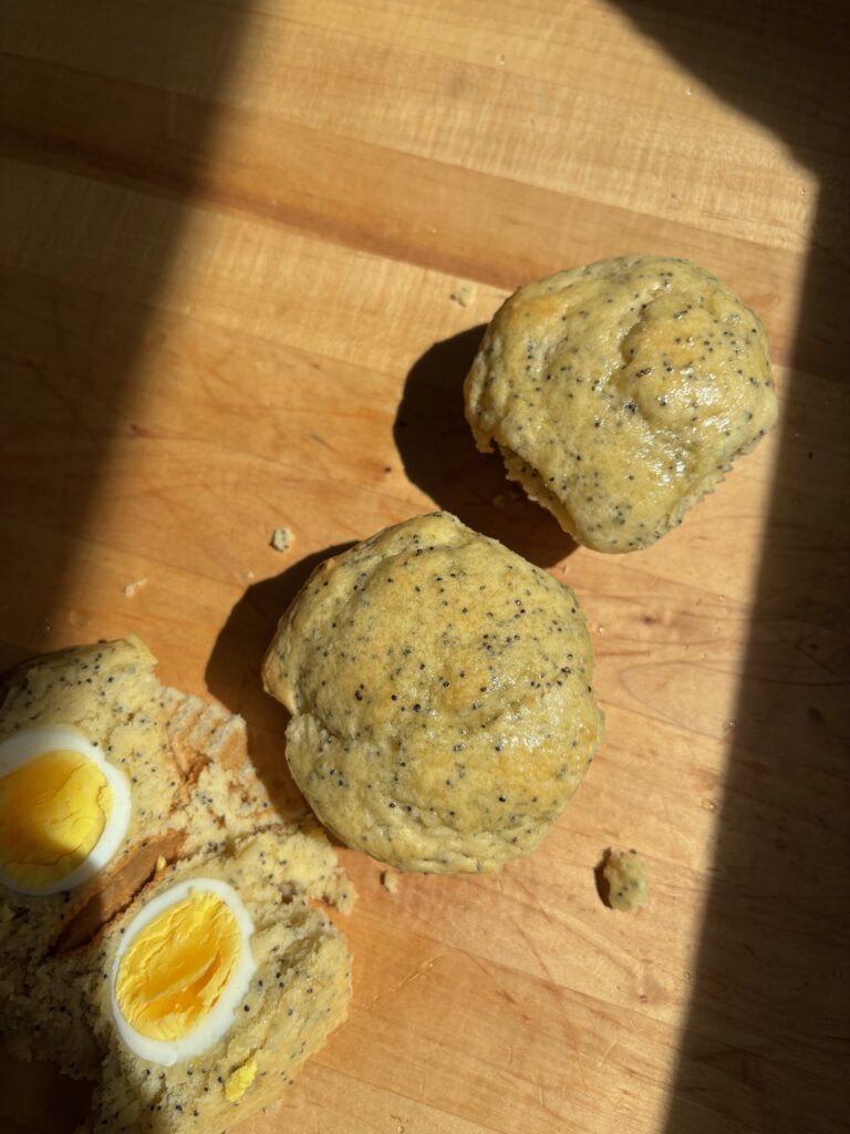 2 Sourdough Discard Lemon Poppyseed Muffins, one cut in the middle with a hardboiled egg inside.