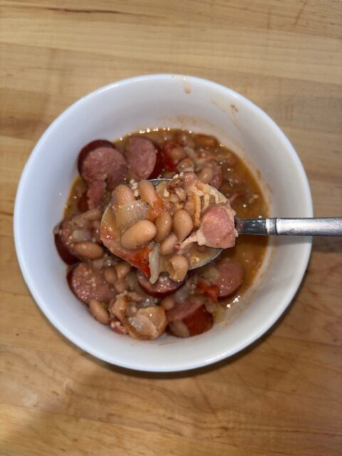 Bowl of frijoles charros with a spoon scooping out a scoop.